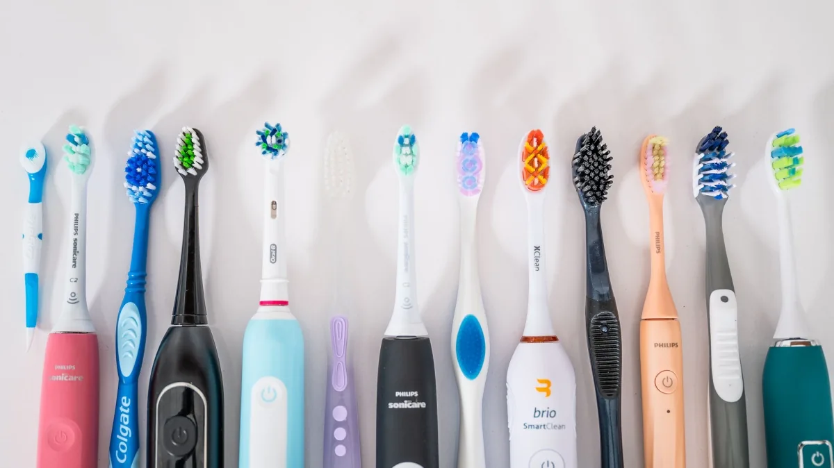 Row of manual and electric toothbrushes against a white background