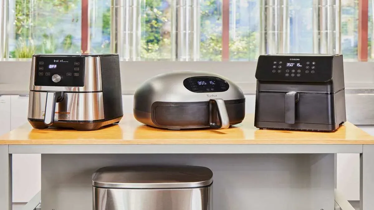 Three air fryers side by side on a kitchen counter