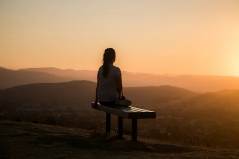Woman sitting calmly overlooking mountains